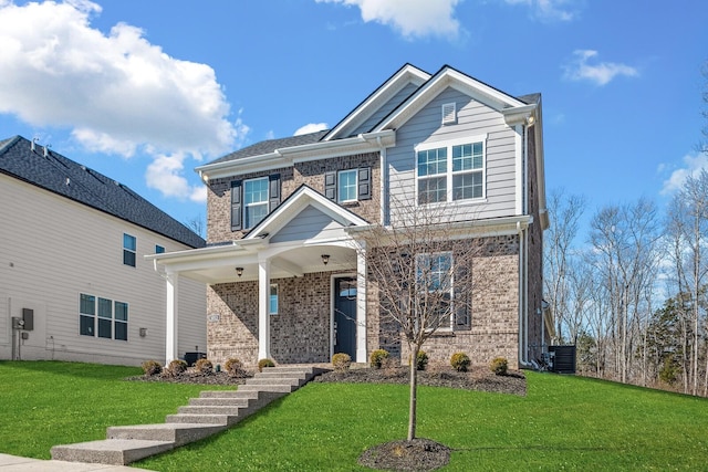 craftsman-style house with central air condition unit, a front yard, and brick siding