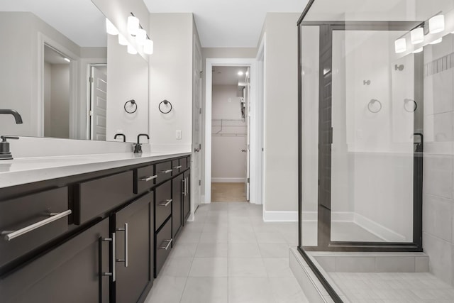 full bathroom with a walk in closet, double vanity, a stall shower, tile patterned flooring, and baseboards