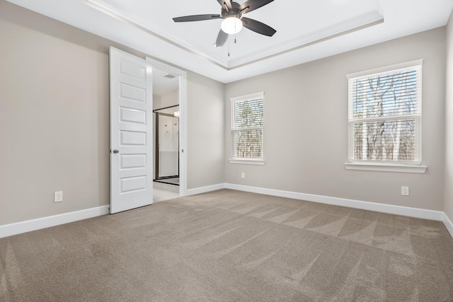 carpeted spare room with ceiling fan, baseboards, and a raised ceiling