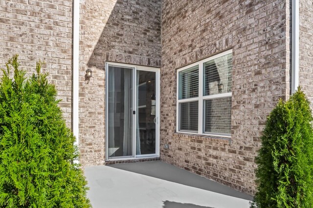 entrance to property featuring brick siding and a patio area