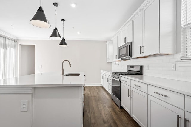 kitchen with ornamental molding, appliances with stainless steel finishes, a sink, and a kitchen island with sink