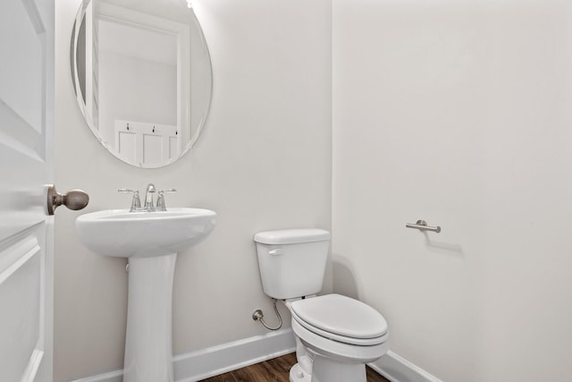 bathroom with toilet, baseboards, and wood finished floors