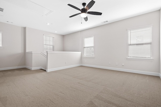 empty room featuring light carpet, baseboards, visible vents, and attic access