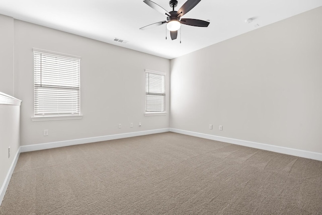 unfurnished room featuring carpet floors, visible vents, baseboards, and a ceiling fan