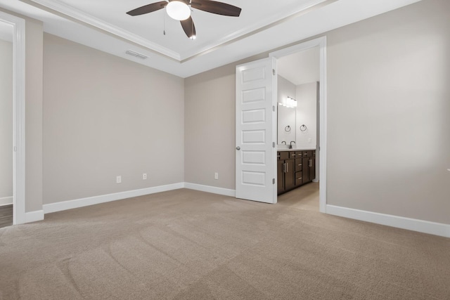 unfurnished bedroom featuring a tray ceiling, visible vents, light carpet, a sink, and baseboards