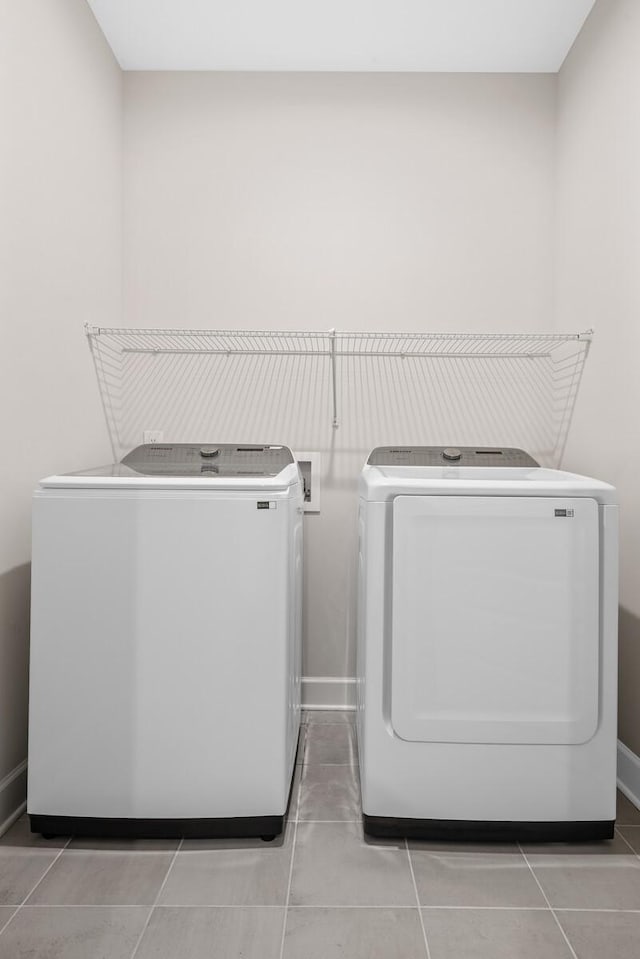 clothes washing area with washer and dryer, laundry area, baseboards, and light tile patterned floors