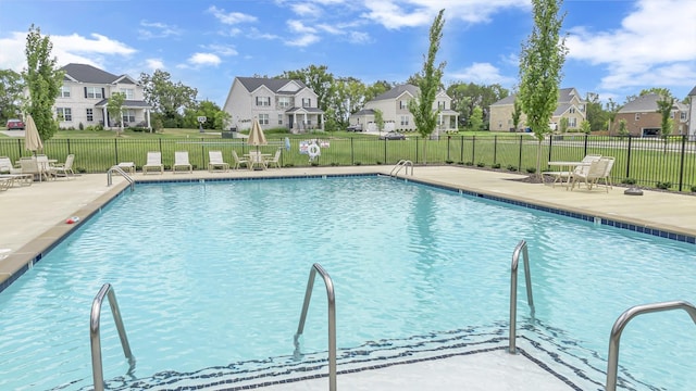 community pool featuring a residential view, fence, and a patio