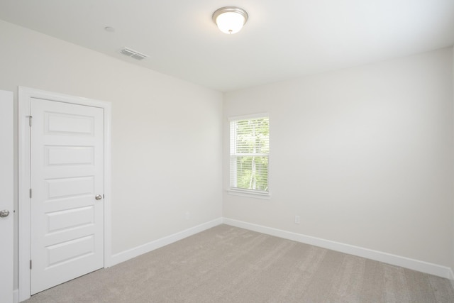 spare room with light carpet, visible vents, and baseboards