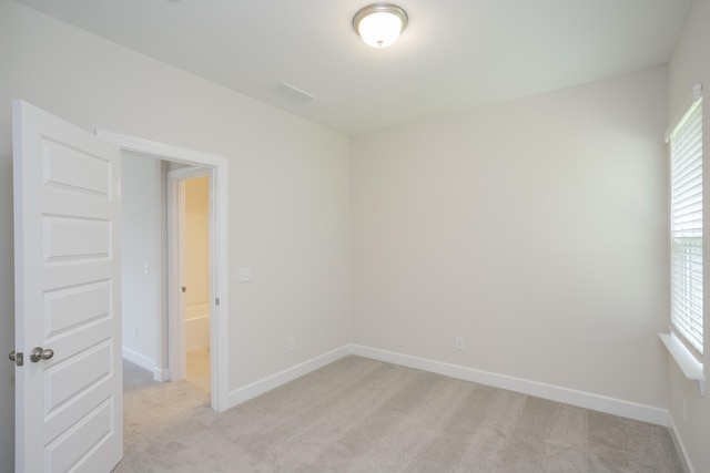 spare room featuring baseboards and light colored carpet