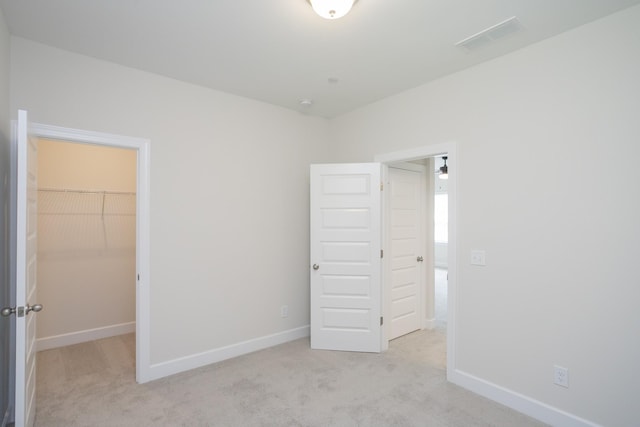 unfurnished bedroom with light colored carpet, visible vents, a spacious closet, and baseboards