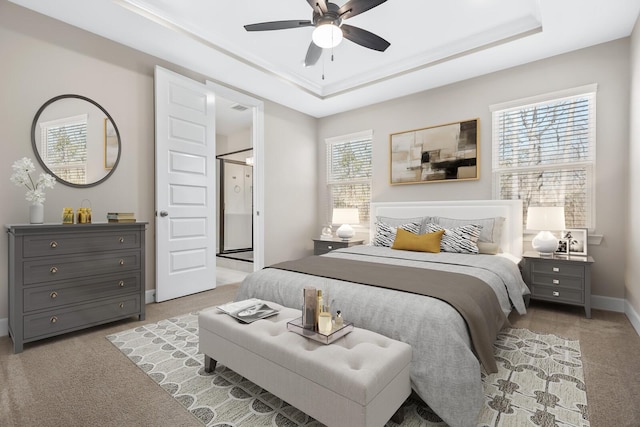 carpeted bedroom with a tray ceiling, multiple windows, and baseboards