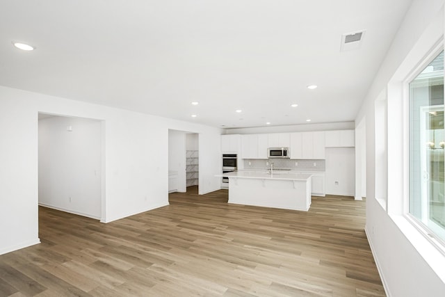 unfurnished living room featuring sink and light hardwood / wood-style floors