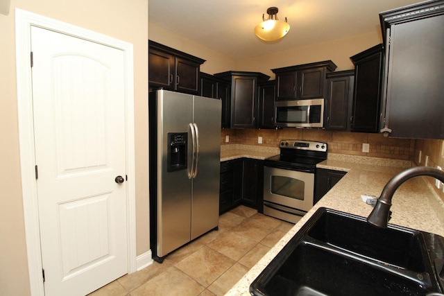 kitchen featuring backsplash, sink, light tile patterned floors, dark brown cabinetry, and stainless steel appliances