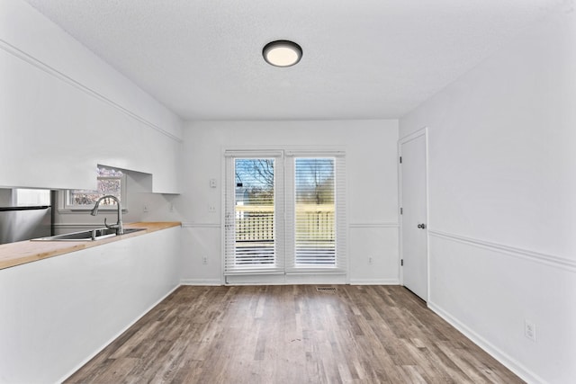 unfurnished dining area with sink, hardwood / wood-style floors, and a textured ceiling