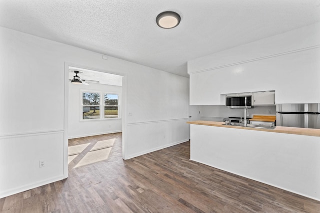 kitchen with ceiling fan, white cabinetry, dark hardwood / wood-style flooring, and fridge