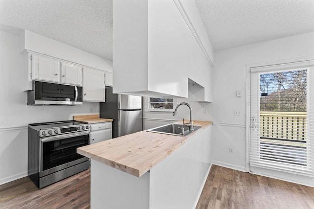 kitchen with kitchen peninsula, sink, white cabinetry, a textured ceiling, and stainless steel appliances