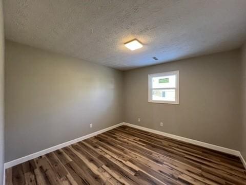 unfurnished room featuring a textured ceiling and dark hardwood / wood-style floors