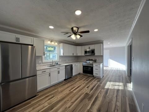 kitchen with white cabinets, crown molding, sink, dark hardwood / wood-style floors, and appliances with stainless steel finishes