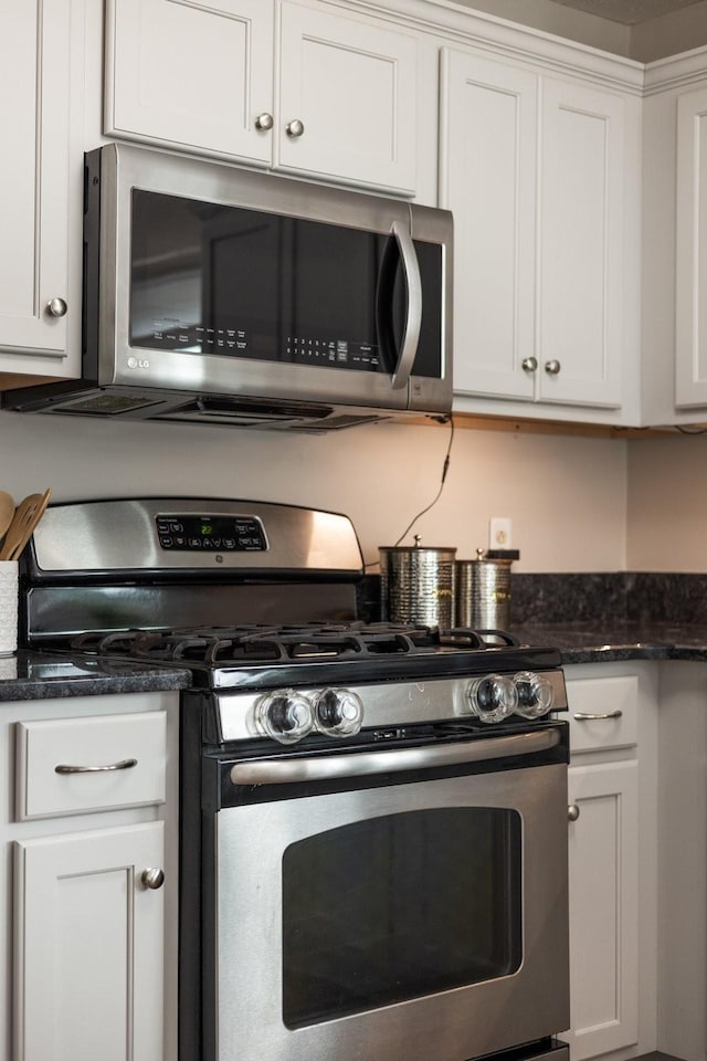 kitchen with white cabinets, appliances with stainless steel finishes, and dark stone countertops