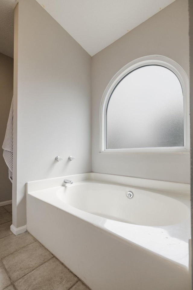 bathroom with tile patterned floors and a bath