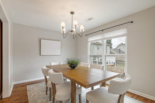 dining area featuring dark hardwood / wood-style flooring and a chandelier