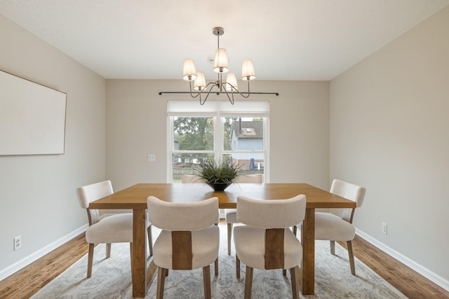 dining space with hardwood / wood-style floors and an inviting chandelier