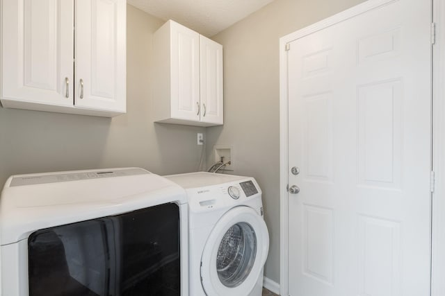 laundry area with washing machine and dryer, cabinets, and a textured ceiling