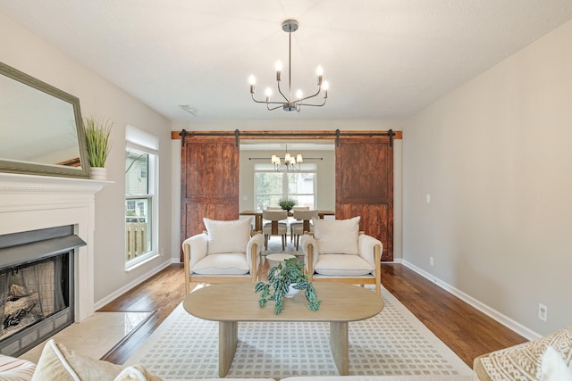 living room with a barn door, wood-type flooring, and a notable chandelier