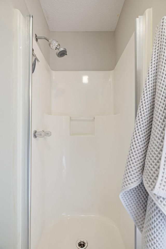 bathroom with a shower and a textured ceiling