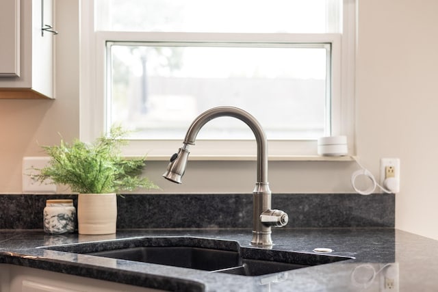 room details featuring white cabinetry, dark stone counters, and sink