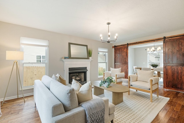 living room with a chandelier, a barn door, hardwood / wood-style flooring, and a wealth of natural light