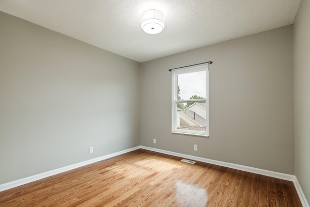 unfurnished room featuring wood-type flooring and a textured ceiling