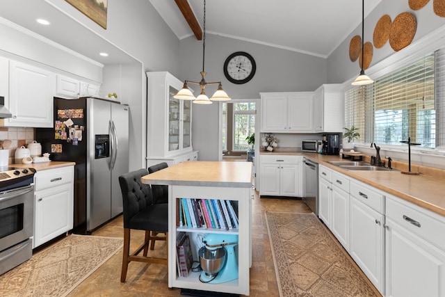 kitchen with decorative light fixtures, backsplash, stainless steel appliances, and white cabinetry