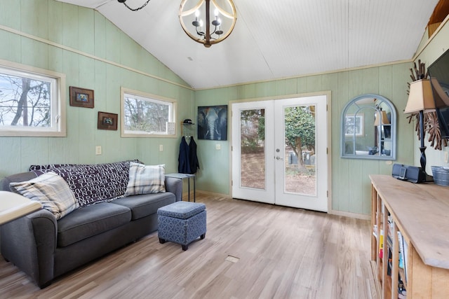 living room with french doors, light hardwood / wood-style floors, lofted ceiling, and a notable chandelier