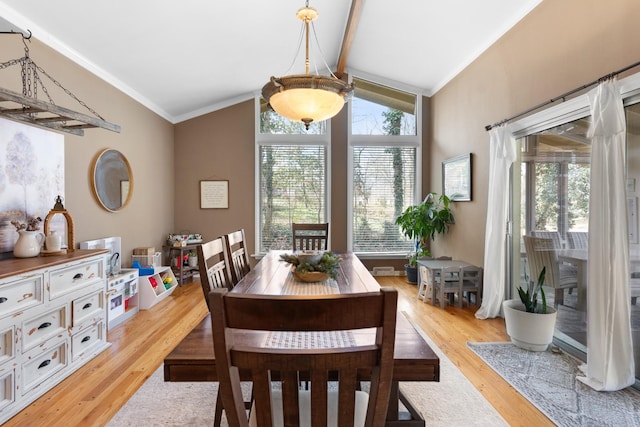 dining space featuring light hardwood / wood-style floors, crown molding, and vaulted ceiling