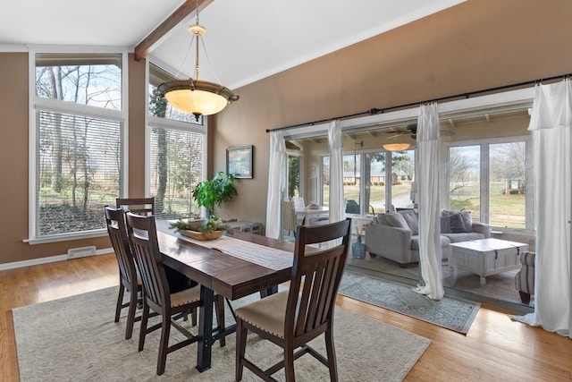 dining room with vaulted ceiling with beams and light hardwood / wood-style floors