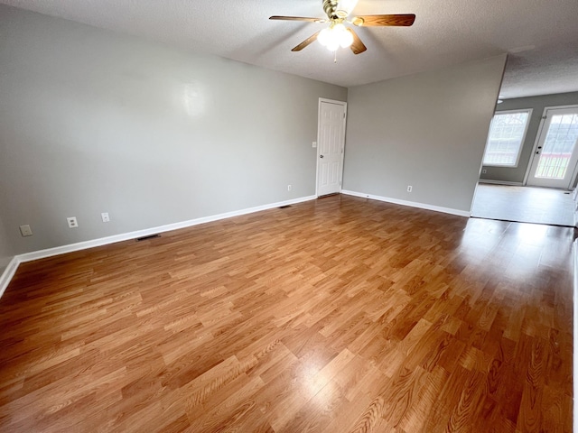 unfurnished room featuring visible vents, ceiling fan, a textured ceiling, wood finished floors, and baseboards