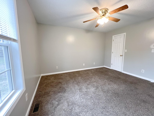 unfurnished room featuring visible vents, baseboards, dark carpet, and a textured ceiling