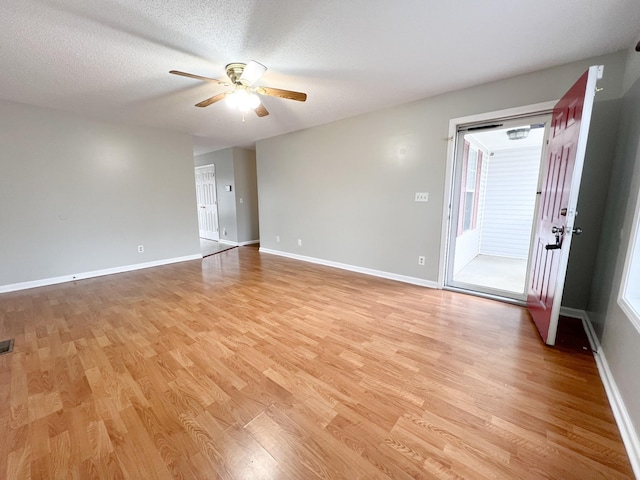 spare room with light wood-style flooring, a textured ceiling, baseboards, and a ceiling fan