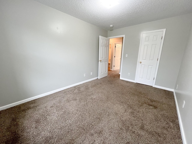 carpeted empty room featuring a textured ceiling and baseboards