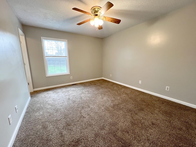 empty room with a ceiling fan, dark carpet, a textured ceiling, and baseboards