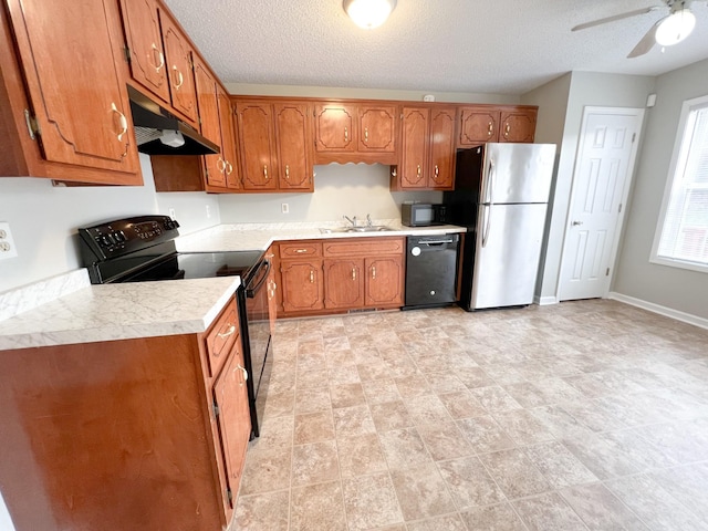 kitchen with black appliances, under cabinet range hood, brown cabinetry, and light countertops