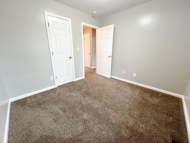 unfurnished bedroom featuring carpet floors, baseboards, and a textured ceiling