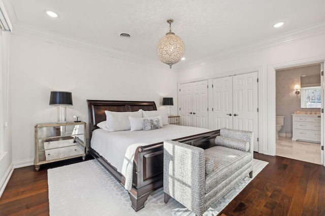 bedroom featuring ornamental molding, dark wood-type flooring, a closet, and ensuite bath