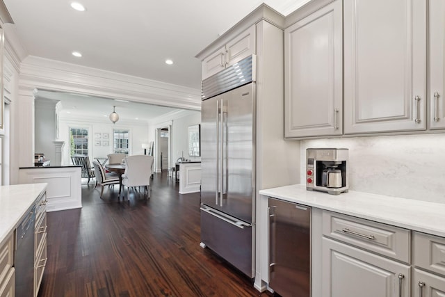 kitchen with light stone countertops, stainless steel built in fridge, dark hardwood / wood-style floors, gray cabinetry, and crown molding