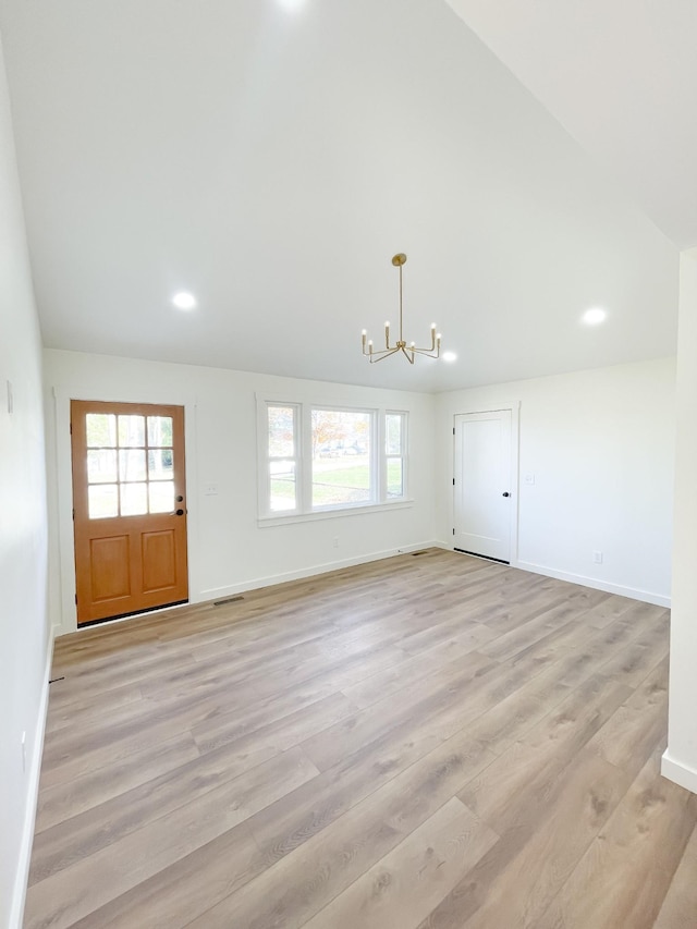 unfurnished living room featuring a chandelier, a wealth of natural light, and light hardwood / wood-style flooring