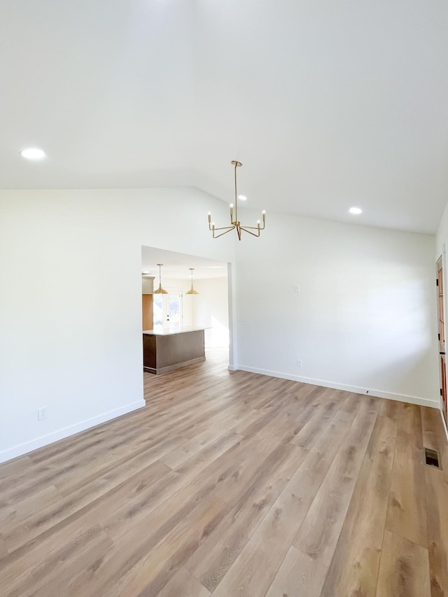 unfurnished living room featuring light hardwood / wood-style floors, vaulted ceiling, and a notable chandelier