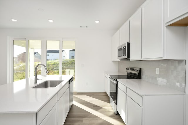 kitchen featuring decorative backsplash, appliances with stainless steel finishes, sink, hardwood / wood-style floors, and white cabinetry