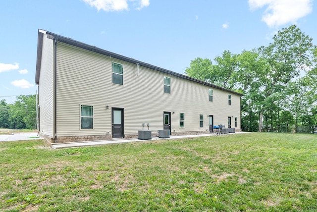 rear view of property featuring central AC unit, a yard, and a patio