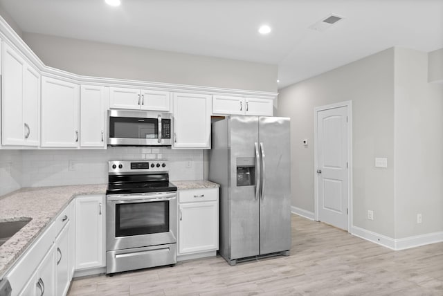 kitchen featuring stainless steel appliances, white cabinetry, and light stone counters